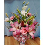 Pink lilies and carnations arranged with white blooms in a ribboned bouquet
