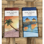 Two Olde Naples chocolate boxes with beach scenes on a woven surface.
