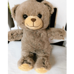 Plush teddy bear with outstretched arms sitting on a white chair