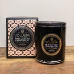 Black glass candle and matching pink and black patterned box on a wooden surface.