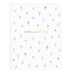 White greeting card with pastel flowers and gold script reading welcome sweet baby