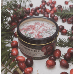Holiday candle in a tin surrounded by cranberries and pine sprigs