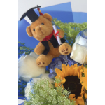 Teddy bear in a graduation cap surrounded by flowers