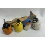 Four painted bird ornaments with twine hangers on a white surface