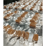 Individually wrapped caramel candies arranged on a metal surface