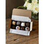 Box of assorted chocolates beside a bouquet of white roses