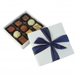 Box of assorted chocolates with a white lid and navy ribbon