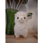 White plush alpaca toy beside a green glass vase
