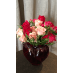 Pink and red roses arranged in a dark red glass vase