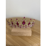 Jeweled pink tiara resting on a small wooden block