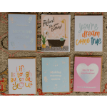 Set of six colorful greeting cards with various messages arranged in two rows on a textured rug.