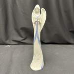 White angel figurine with blue accents standing on a dark surface