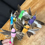Cluster of colorful feather bird ornaments held in a hand
