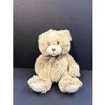 Plush teddy bear with a plaid bow sitting against a dark background