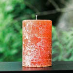 Orange pillar candle with a mottled wax finish