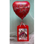 Heart-shaped Valentine balloon above a gift bag with a teddy bear and chocolates