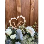 White roses and a pale pink gerbera daisy with a wooden "Love" topper