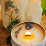 Lit candle in a white tin with stones beside a crystal tree ornament
