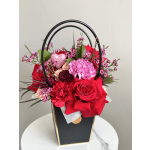 Red roses and pink carnations in a black handled box with a glitter heart