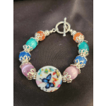 Colorful beaded bracelet with a butterfly charm on dark fabric