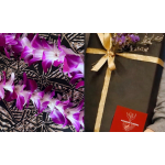 Purple and white orchid flowers arranged beside a black gift box with a gold ribbon.