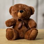 Brown teddy bear with a ribbon bow sitting on a surface