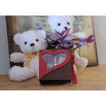 Two white teddy bears with a potted purple plant and a heart-shaped candy box