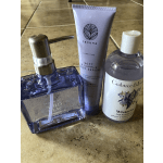 Three bath and body products on a tiled surface, including a soap dispenser and lotion tubes.
