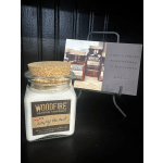 Glass jar candle with a cork lid and label on a black display stand