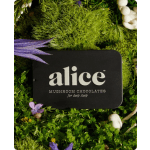 Black tin of Alice mushroom chocolates surrounded by moss and small flowers