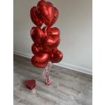 Cluster of red heart-shaped balloons with a small heart gift box on the floor