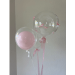 Three pink and clear balloons tied with ribbons