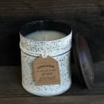 White speckled candle in a jar with a lid beside it