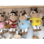 Plush cow toys in colorful sweaters hanging on display