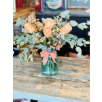 Peach roses in a blue glass jar with a pink ribbon
