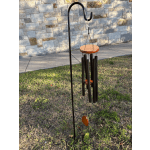 Black metal wind chime hanging outdoors on a stand