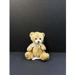 Small teddy bear with a polka-dot ribbon sitting on a dark background