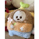 Plush toy with a fuzzy brown face and pastel flower details