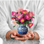 Pink and white flowers in a blue patterned vase held in two hands