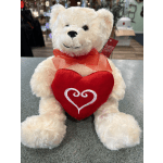 White teddy bear holding a red heart and wearing a red ribbon