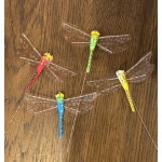 Five colorful dragonfly decorations on a wood surface
