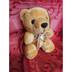 Plush teddy bear with a ribbon bow on pink fabric