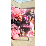 Pink and black balloon display beside a "50 & Fabulous" party sign