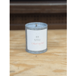 A scented candle in a metal tin with a white label