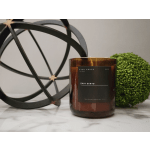 Amber glass candle labeled Palo Santo beside a green decorative sphere