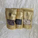 Three gold pouches of chocolate candies on a white textured backdrop