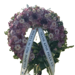 Large standing wreath of purple and mauve flowers with two vertical printed sympathy ribbons.