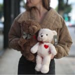 Person holding two teddy bears with ribbon bows