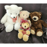 Three teddy bears and a small plush bear with a heart sit on dark fabric.