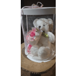 White teddy bear in a clear gift box with a pink flower bouquet